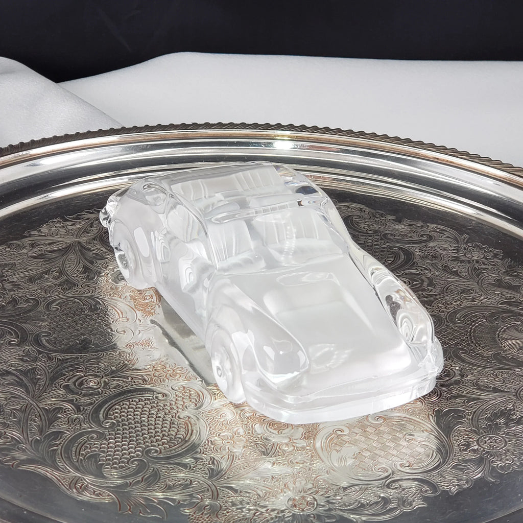 Vintage clear glass car figurine displayed on an ornate silver tray.