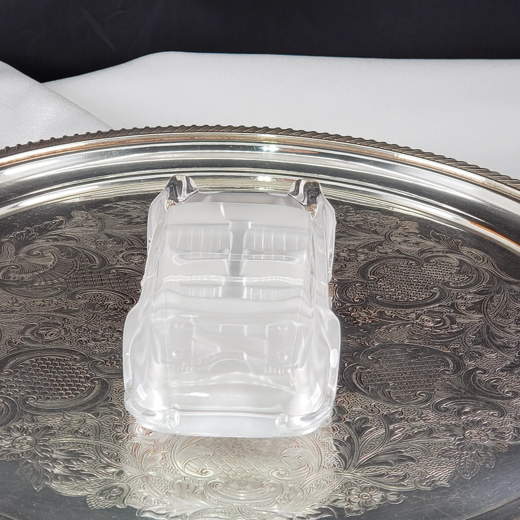 Clear vintage glass car figurine resting on an ornate silver tray.