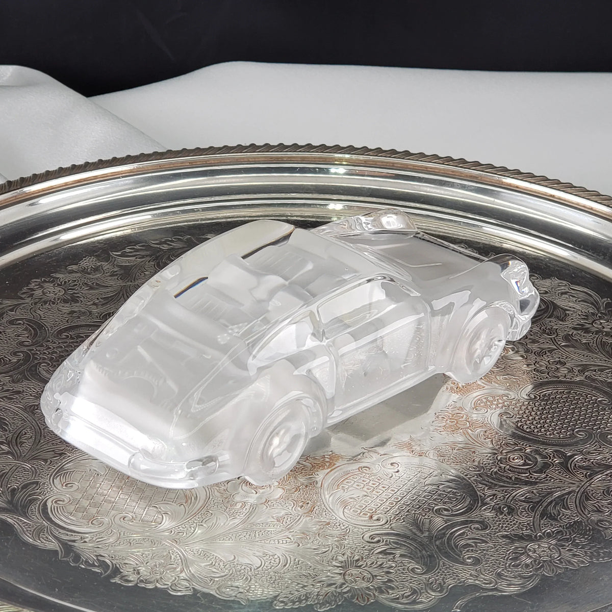 Vintage clear glass car figurine on an ornate silver decorative tray
