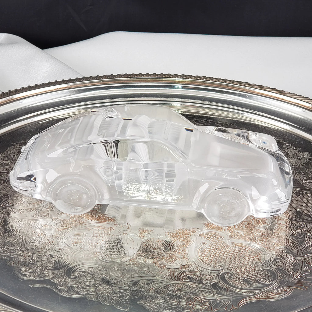 Vintage clear glass car figurine displayed on a decorative silver tray