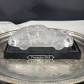 Clear crystal Porsche 911 car figurine on a black base and silver tray.