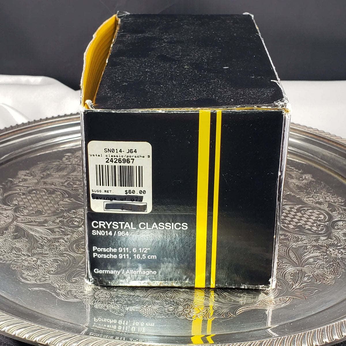 Vintage Porsche 911 crystal collectible in a black and yellow box on a silver tray.
