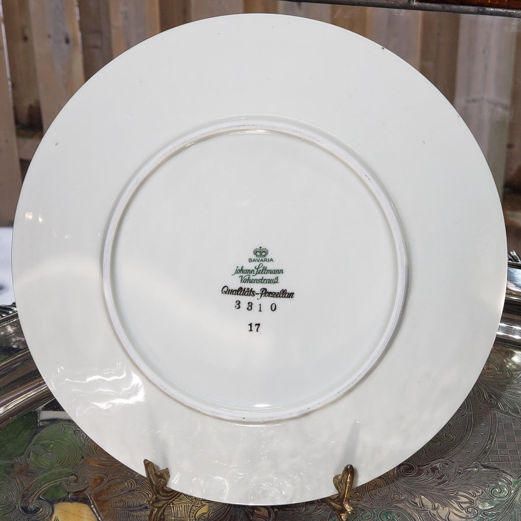 A white porcelain plate with a green and black logo and text on it, placed on a metal stand.