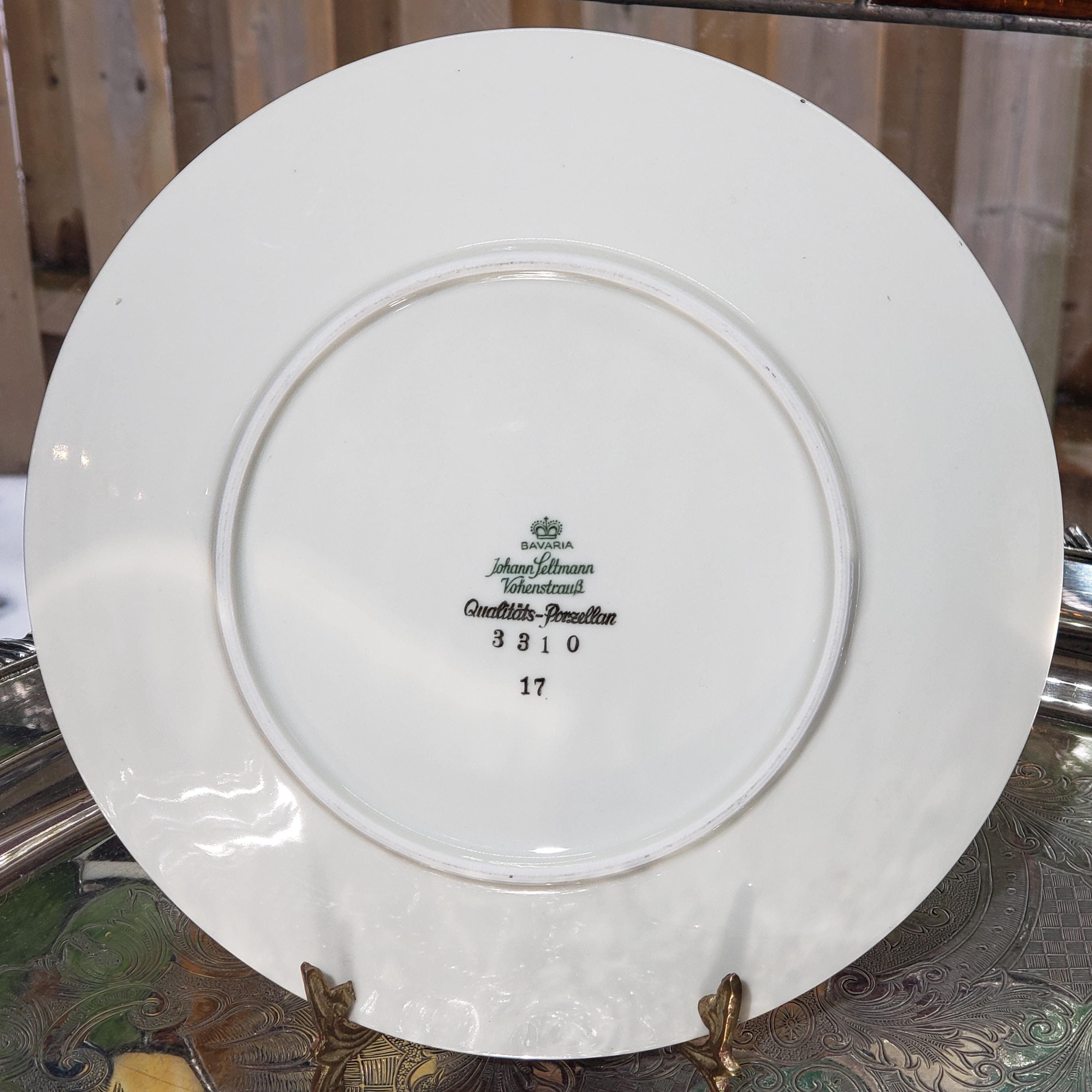 A white porcelain plate with a green and black logo and text on it, placed on a metal stand.