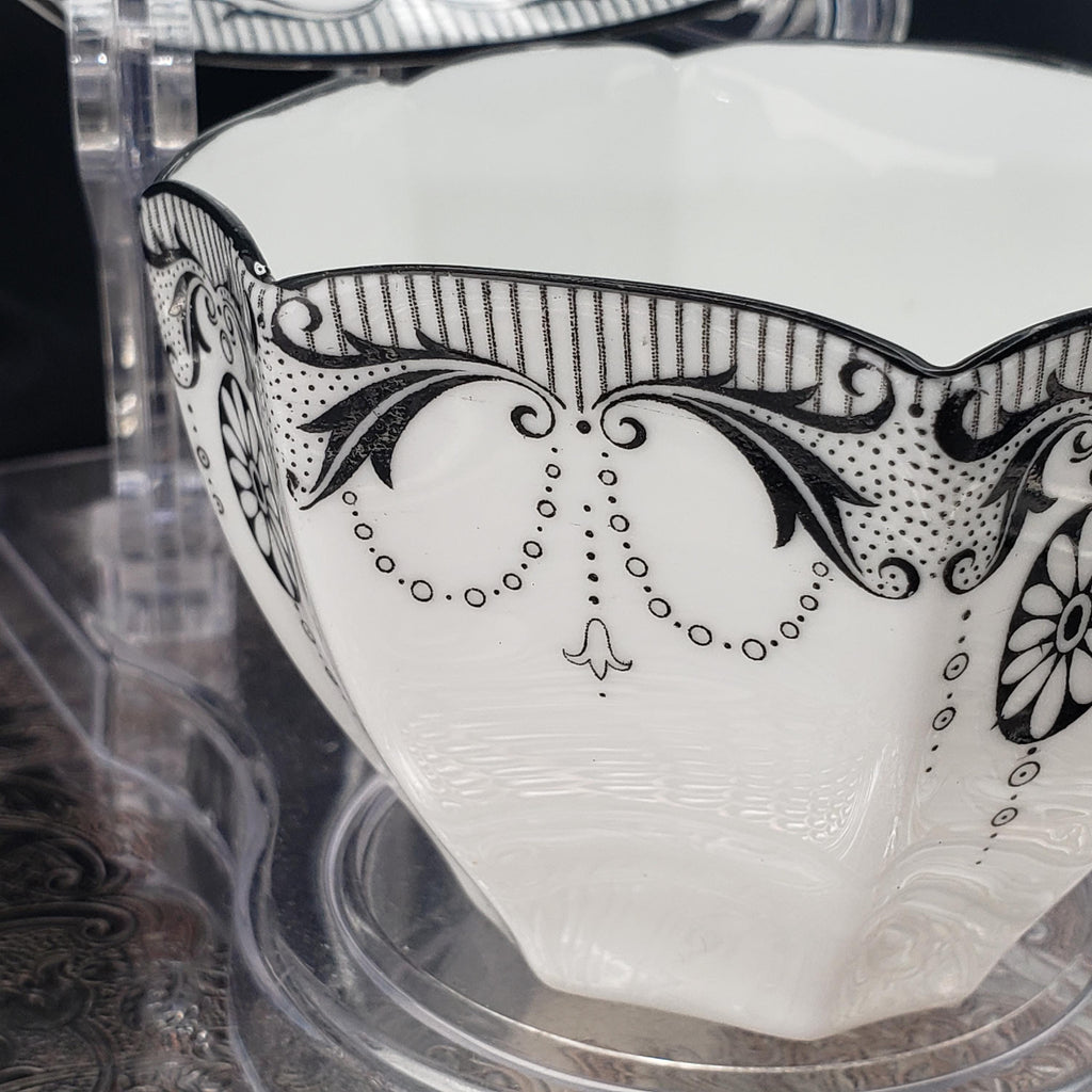 A close-up image of a white ceramic bowl with black decorative patterns and designs, including floral and geometric elements.
