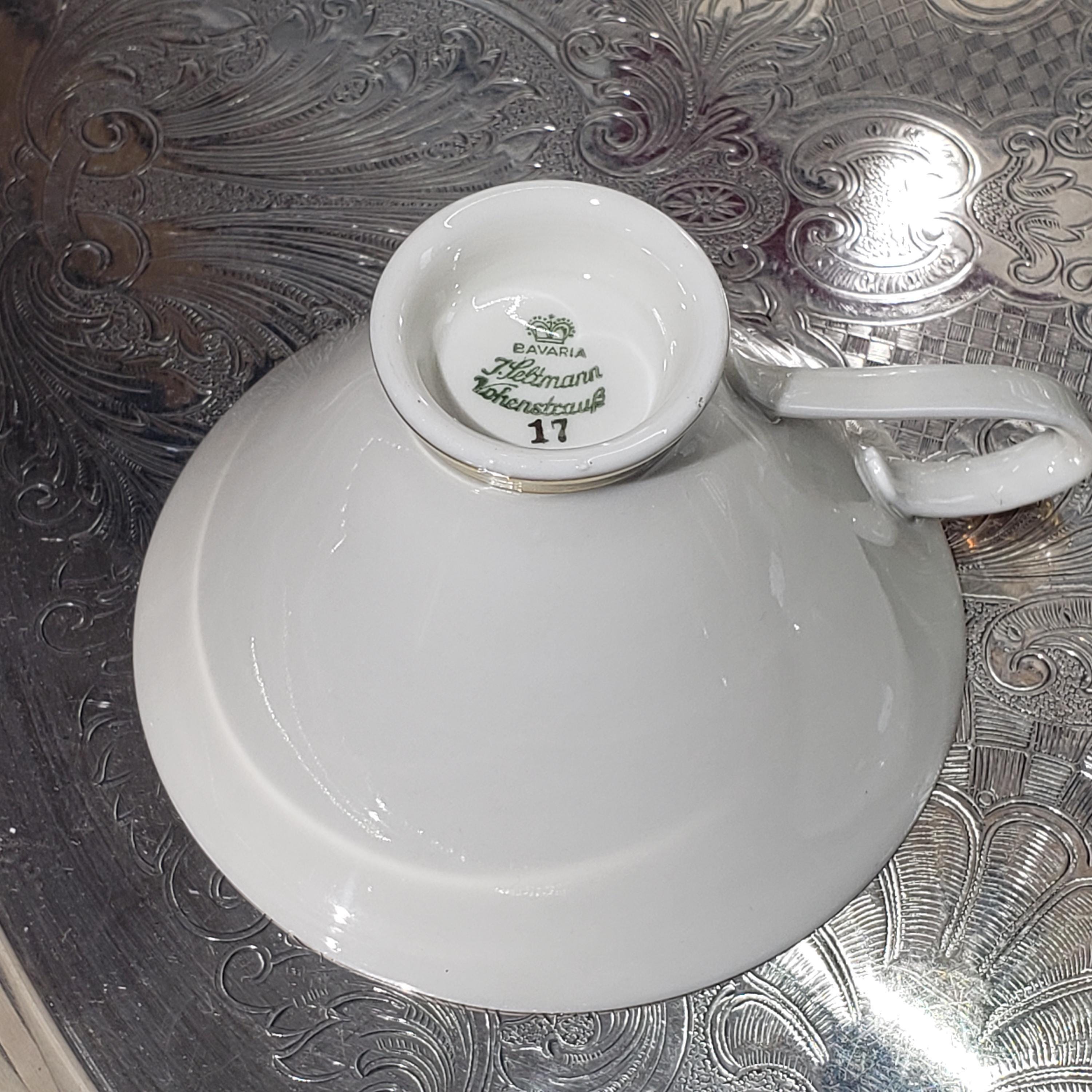 A white porcelain cup with a handle, placed on a decorative metal surface.