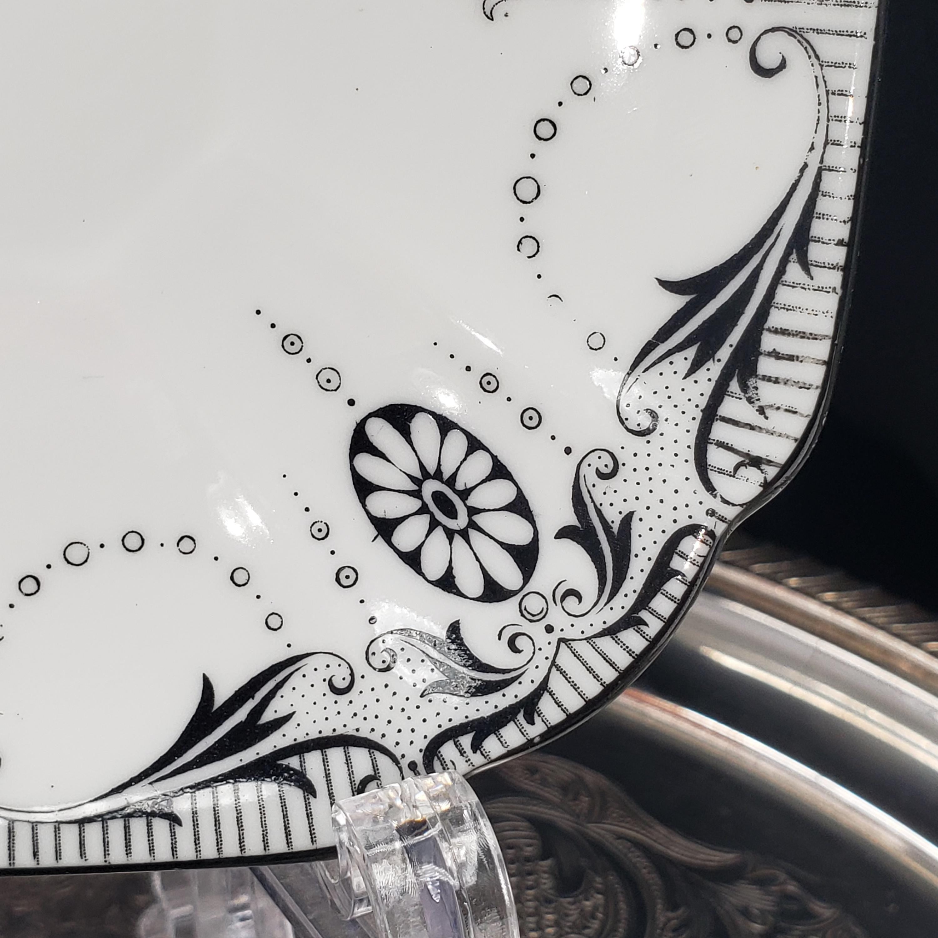 a close-up view of a decorative plate with a black and white floral design.