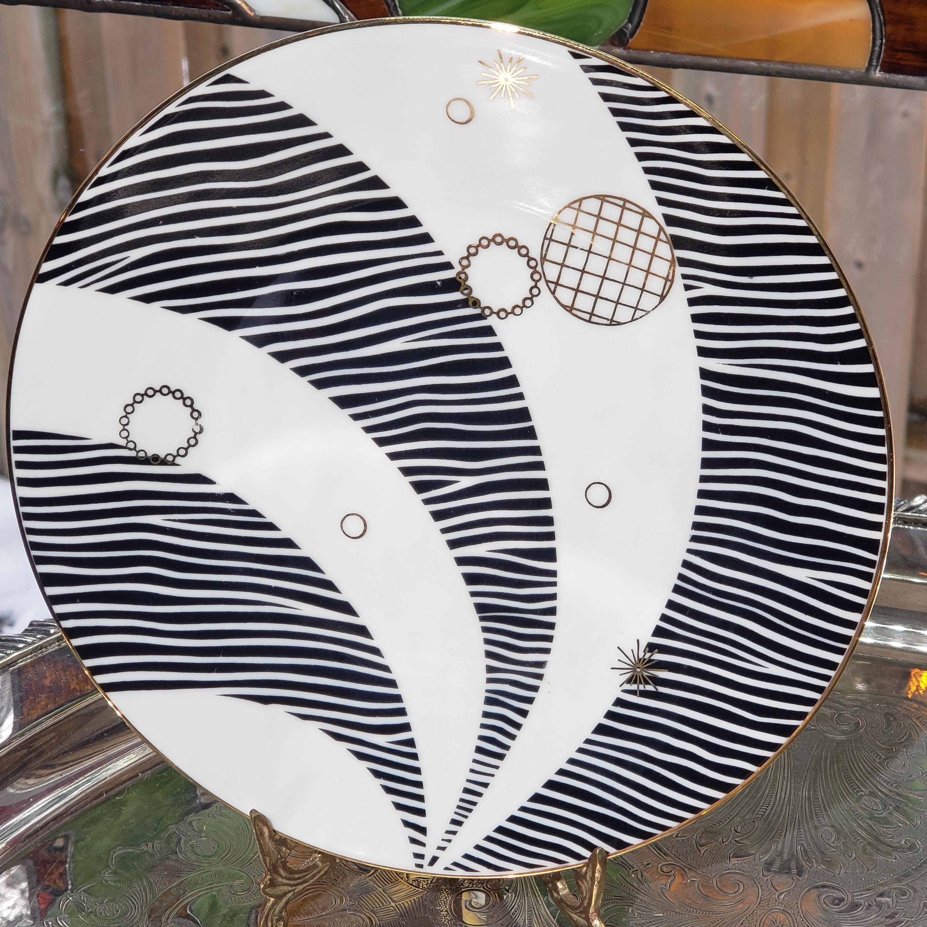 a decorative plate with a black and white striped pattern and various geometric shapes, including circles and lines, creating an abstract and visually striking design.
