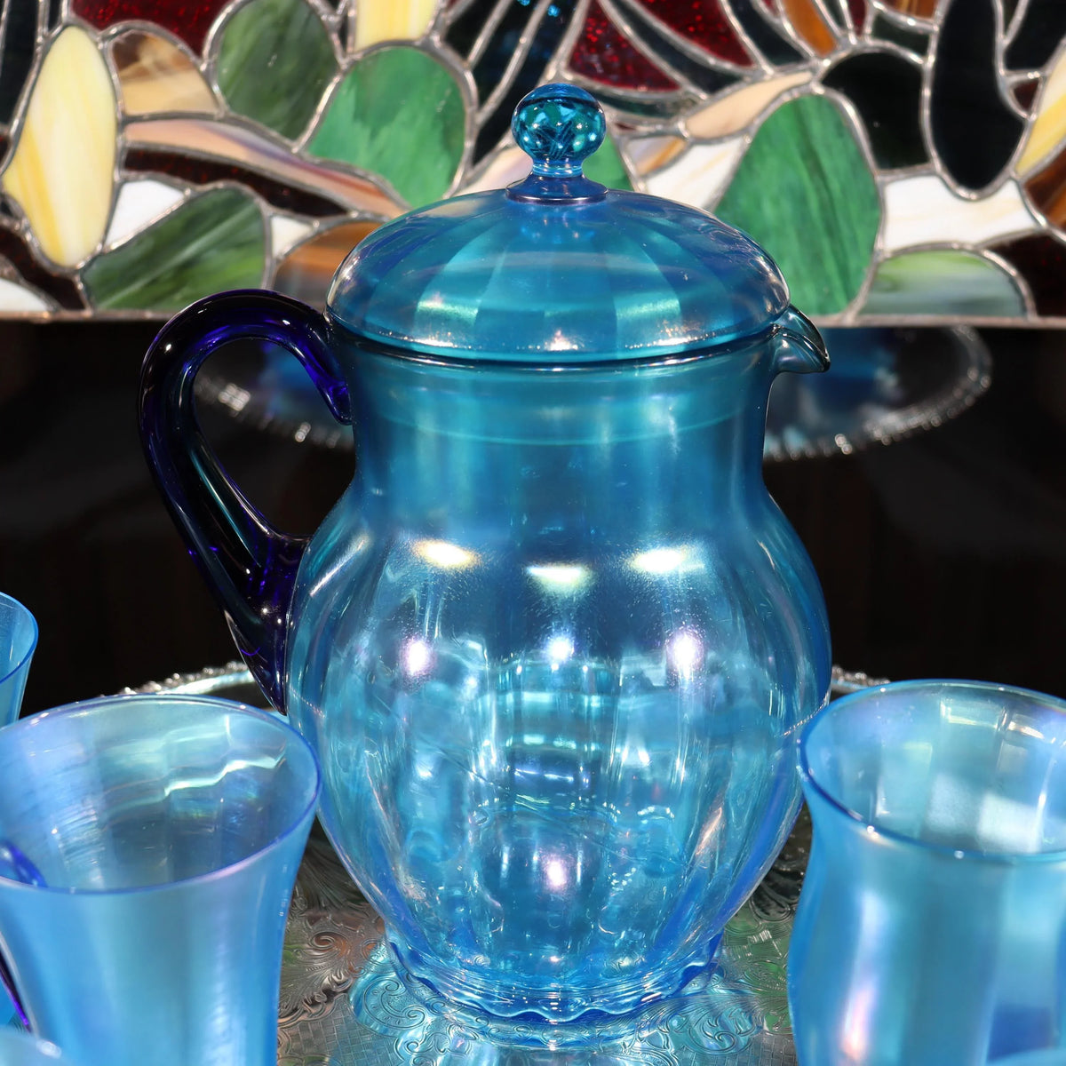 Light blue iridescent Fenton Glass pitcher with two different styles of 4 glasses. Celeste Pattern from the 1920s