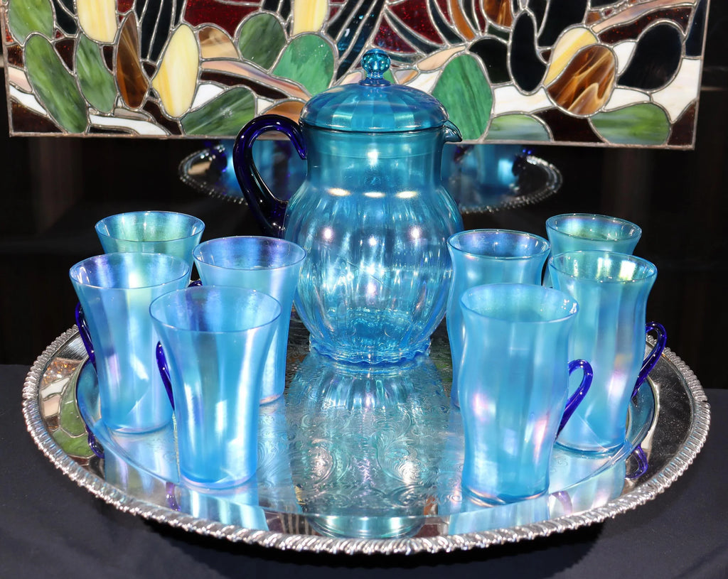 Light blue iridescent Fenton Glass pitcher with two different styles of 4 glasses. Celeste Pattern from the 1920s
