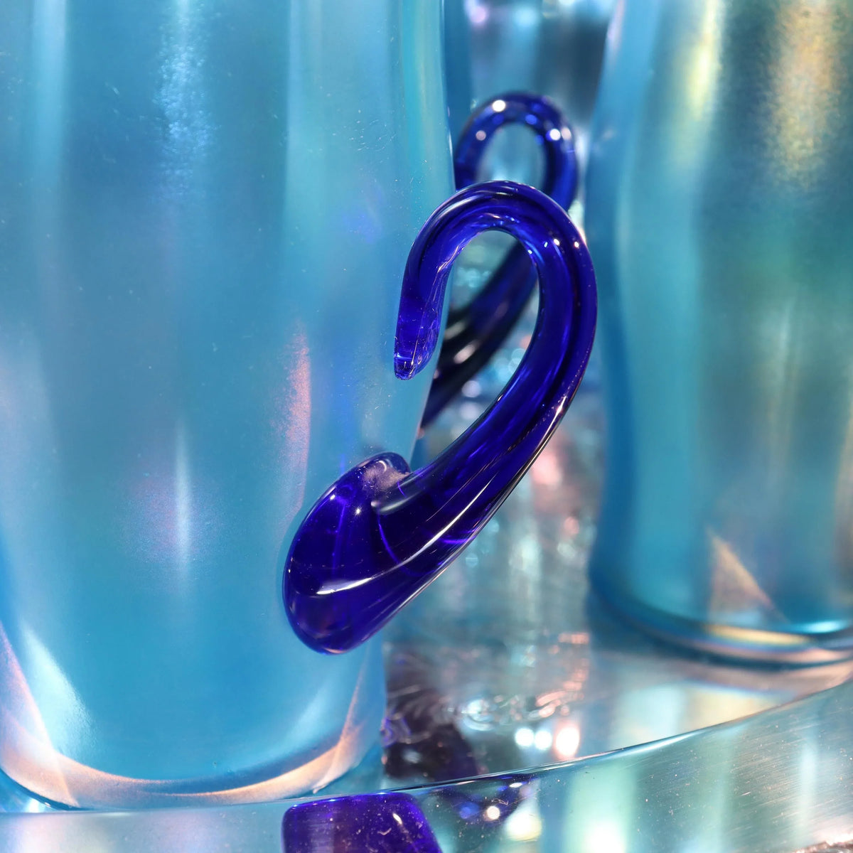 Light blue iridescent Fenton Glass pitcher with two different styles of 4 glasses. Celeste Pattern from the 1920s