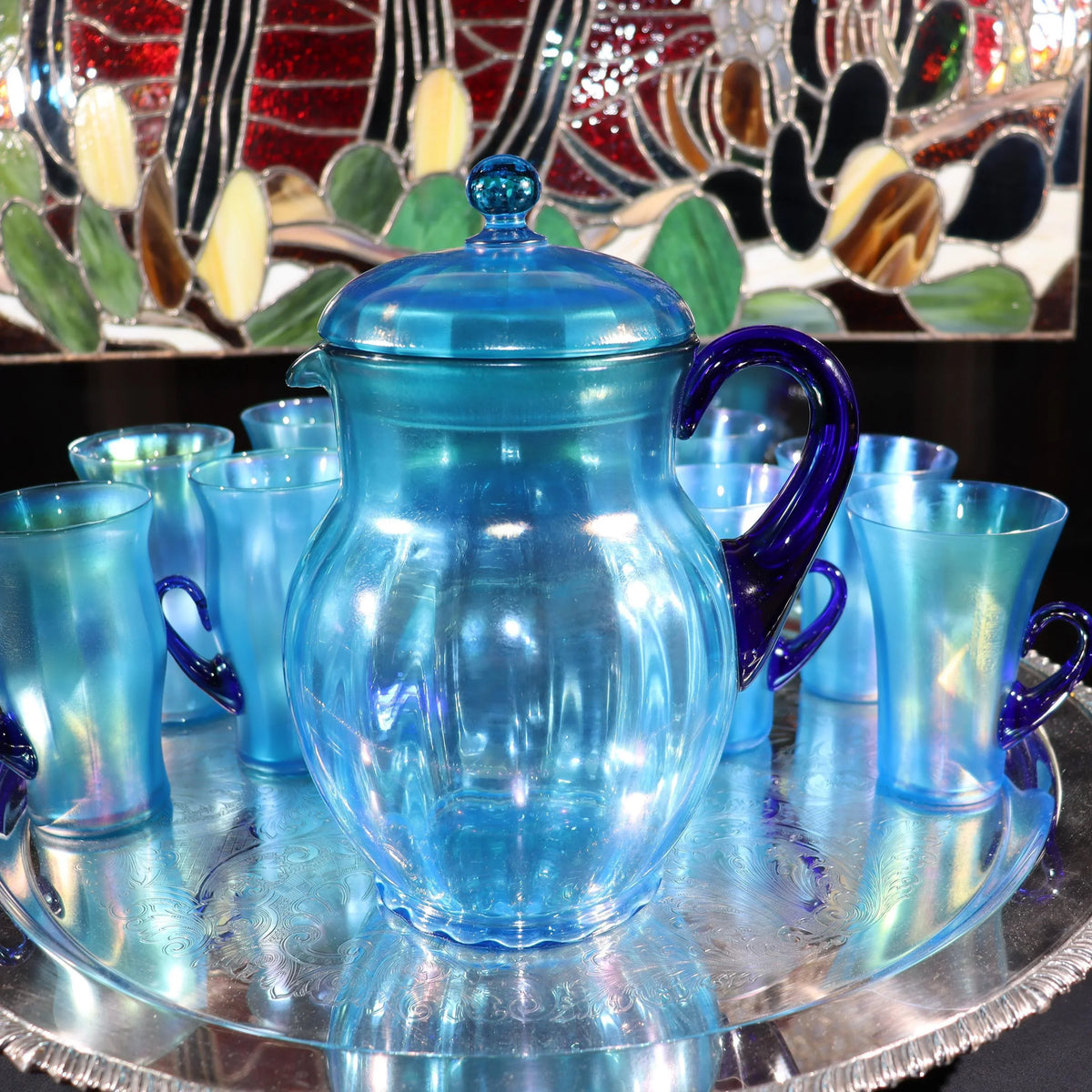 Light blue iridescent Fenton Glass pitcher with two different styles of 4 glasses. Celeste Pattern from the 1920s