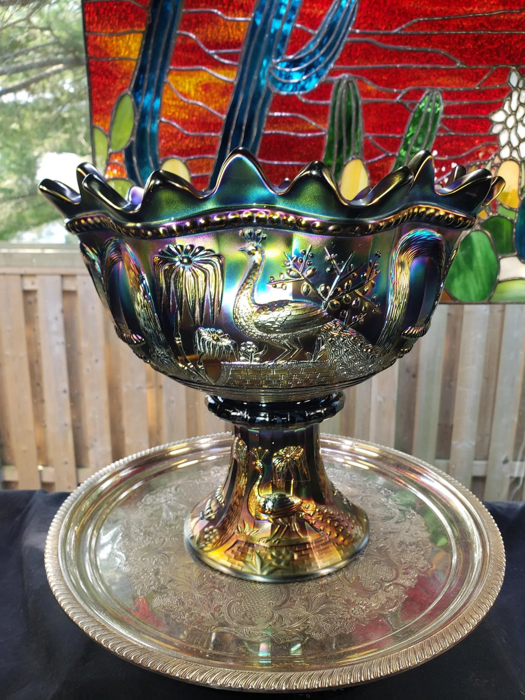 a decorative bowl with a peacock design, placed on a silver tray.