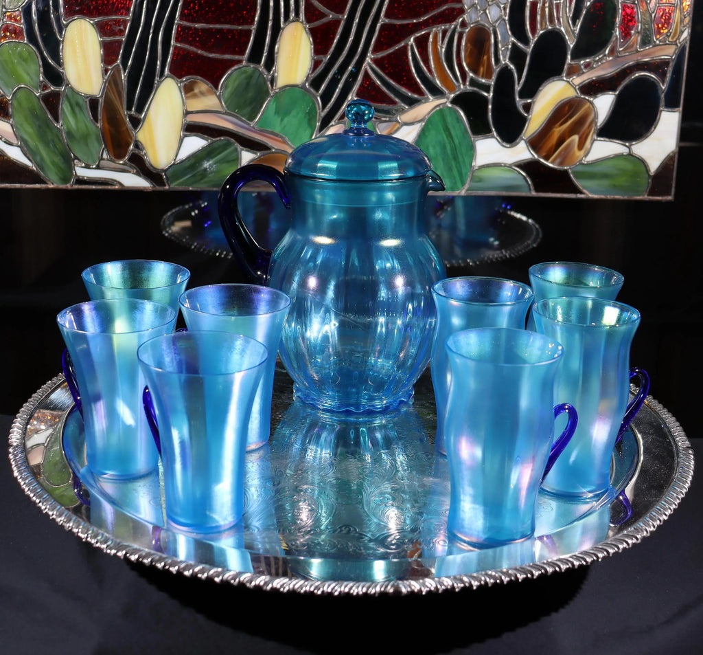 Light blue iridescent Fenton Glass pitcher with two different styles of 4 glasses. Celeste Pattern from the 1920s
