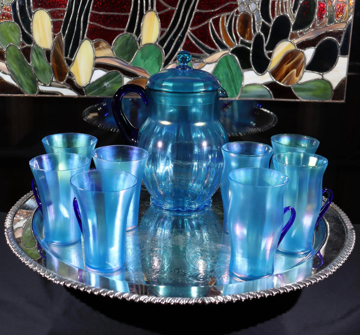 Light blue iridescent Fenton Glass pitcher with two different styles of 4 glasses. Celeste Pattern from the 1920s
