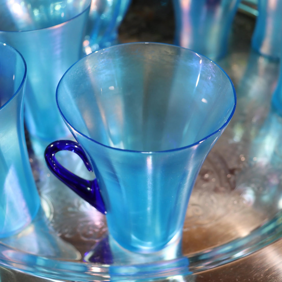 Light blue iridescent Fenton Glass pitcher with two different styles of 4 glasses. Celeste Pattern from the 1920s