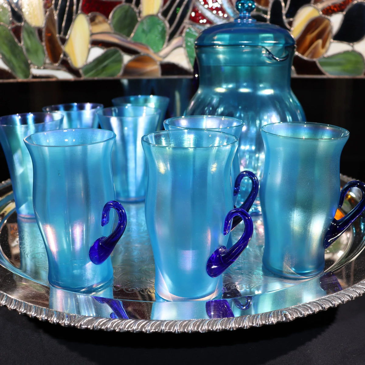 Light blue iridescent Fenton Glass pitcher with two different styles of 4 glasses. Celeste Pattern from the 1920s