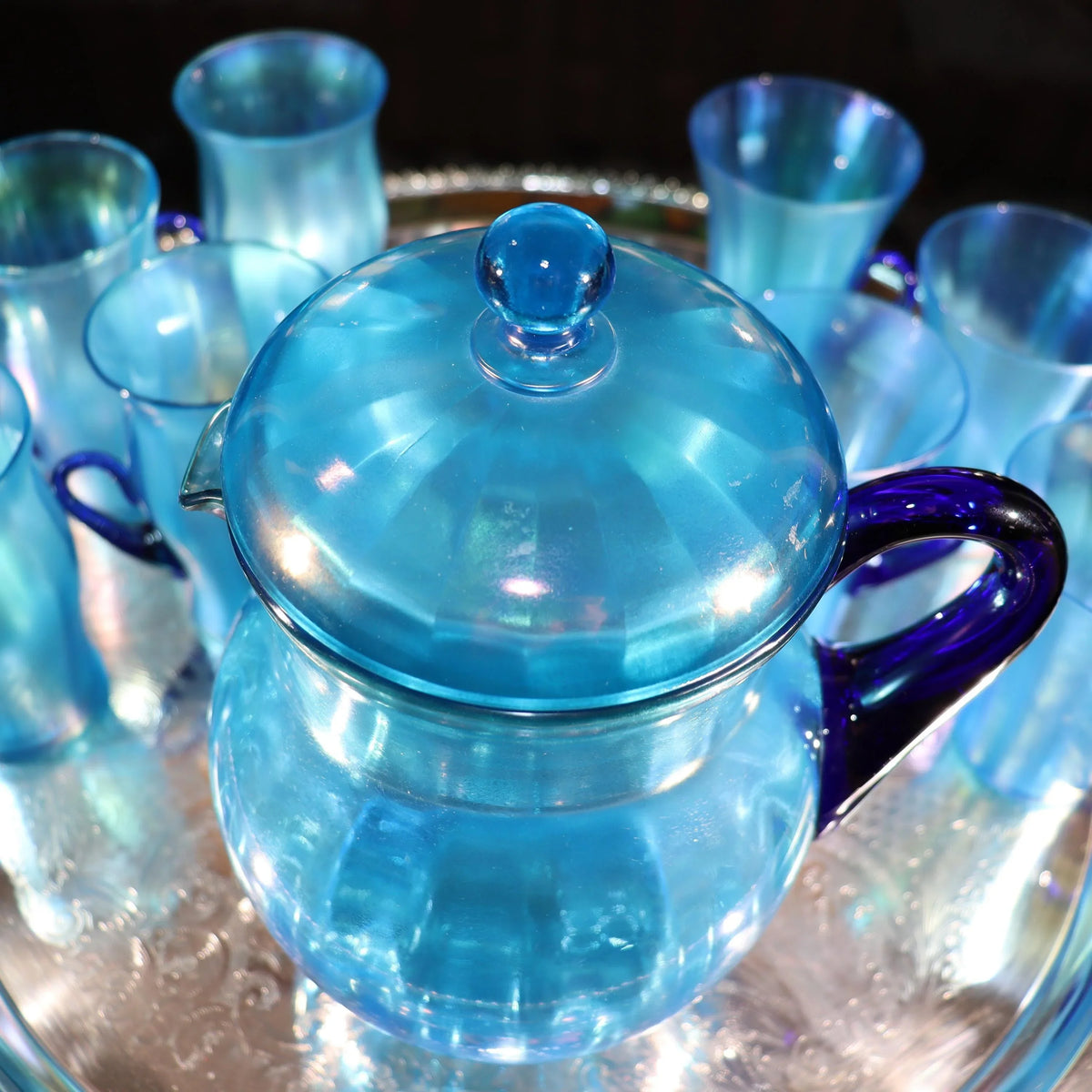 Light blue iridescent Fenton Glass pitcher with two different styles of 4 glasses. Celeste Pattern from the 1920s