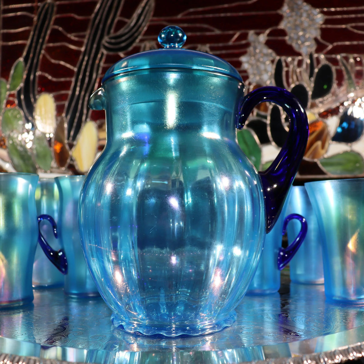 Light blue iridescent Fenton Glass pitcher with two different styles of 4 glasses. Celeste Pattern from the 1920s